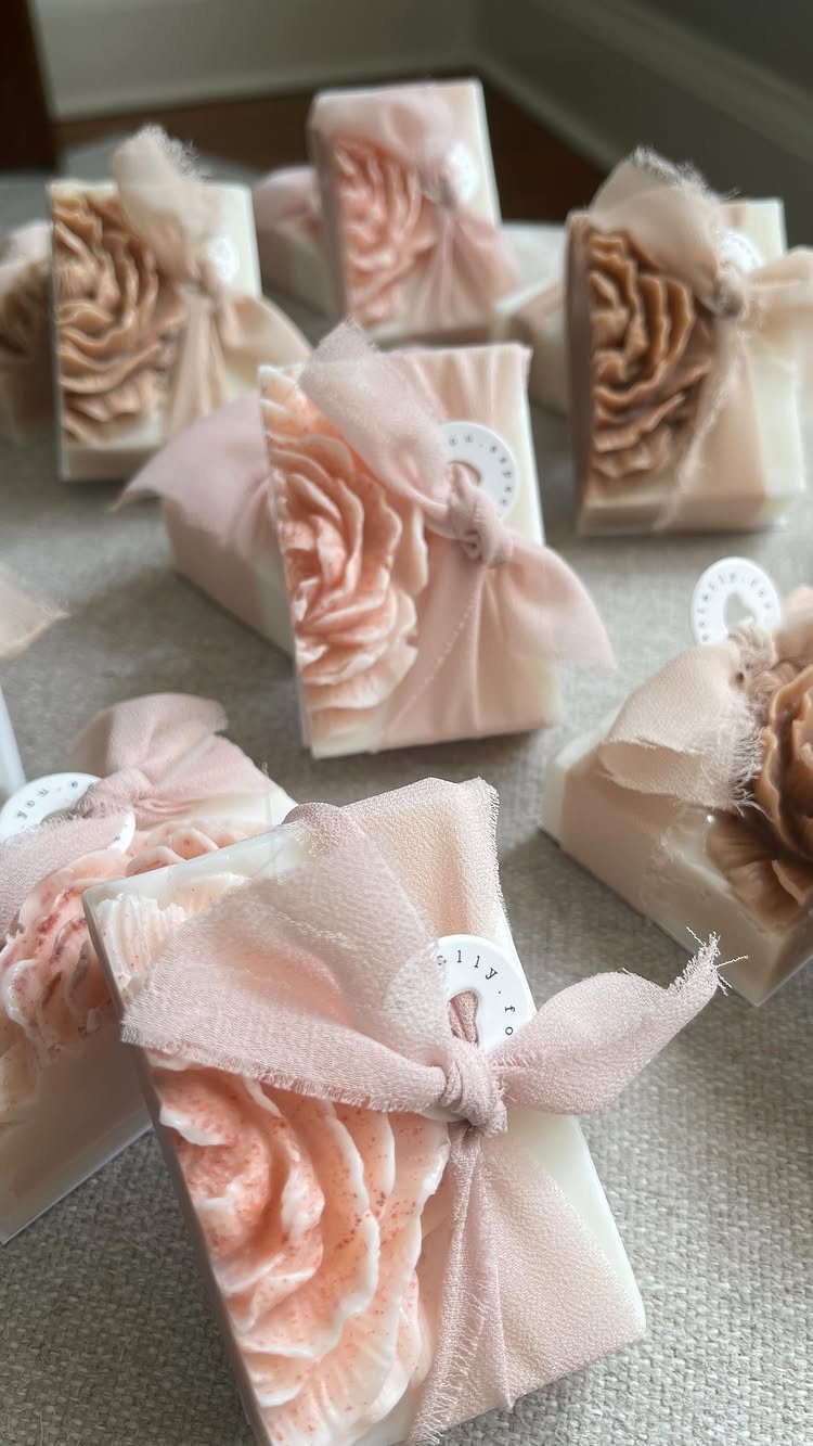 Handmade white soaps with peach floral carvings wrapped in sheer fabric bows.