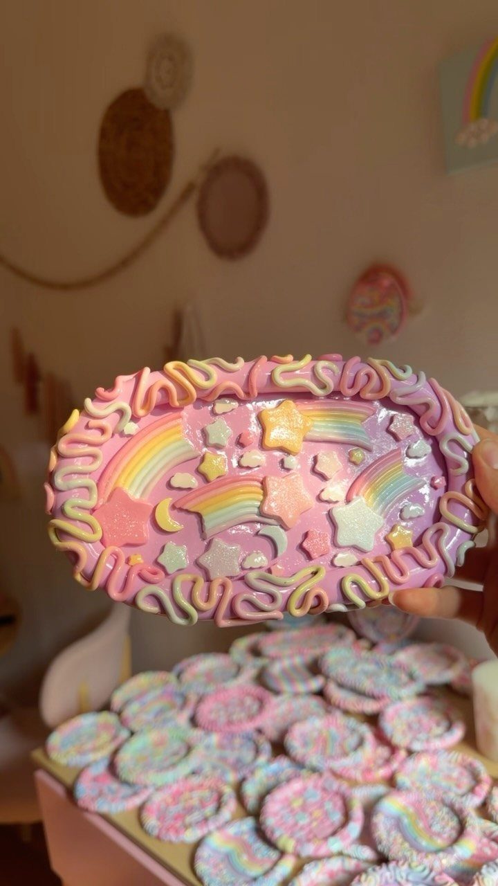 Pink clay trinket dish with rainbows and stars held over other colorful dishes.