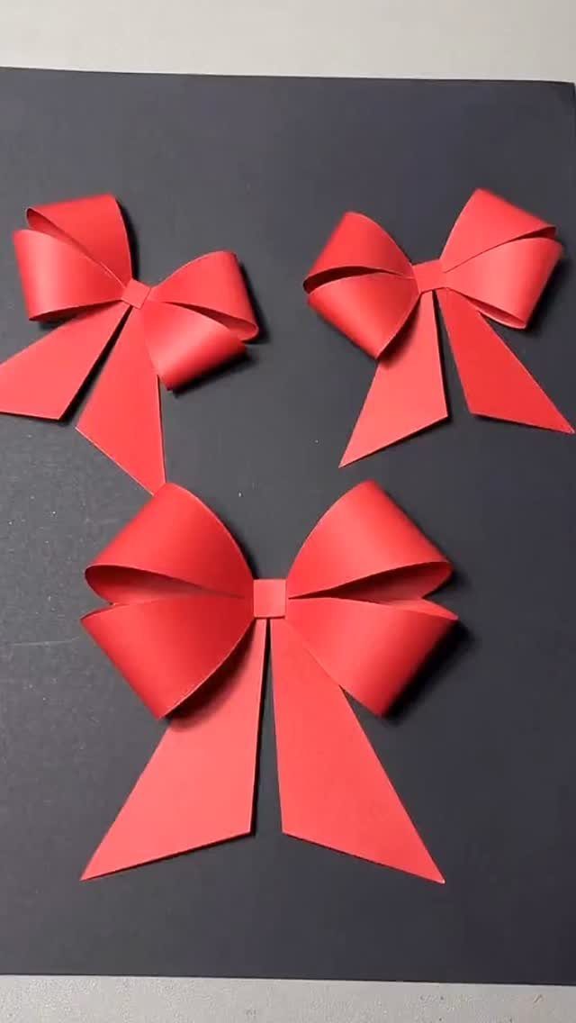 Three red paper bows arranged on a solid black background.