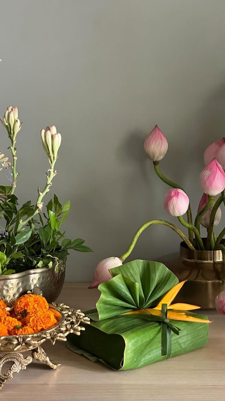 Gift wrapped in green banana leaves with a yellow flower and pink lotus flowers.