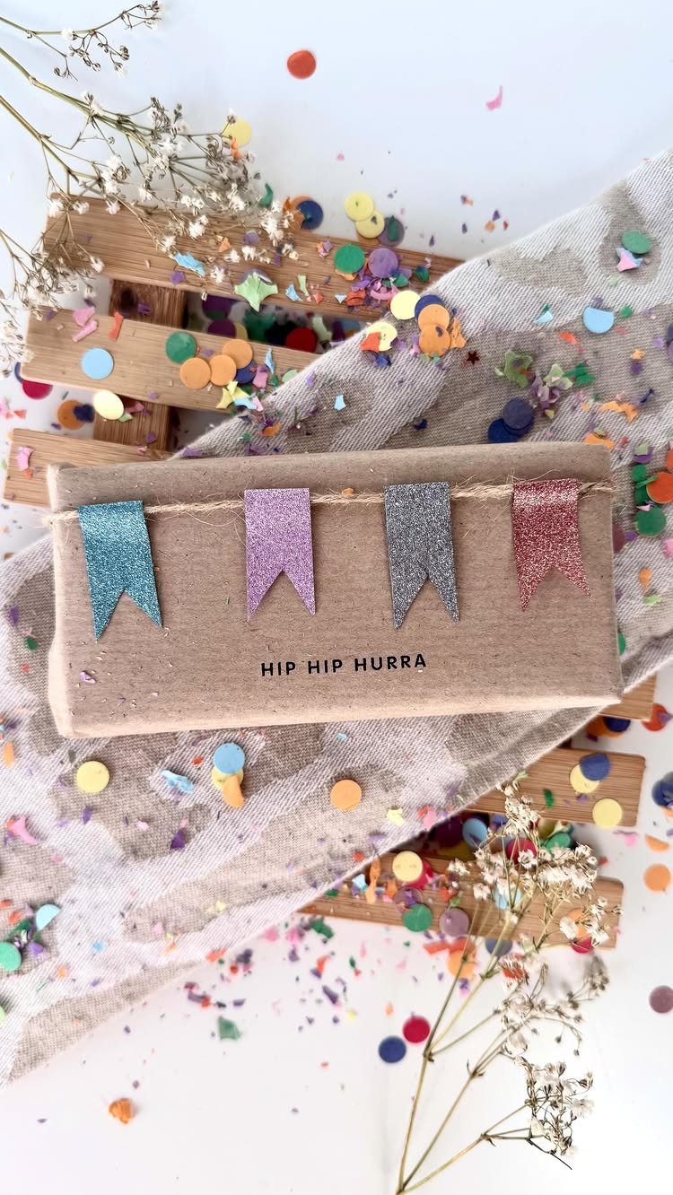 Brown paper wrapped gift with colorful glitter bunting flags and festive confetti