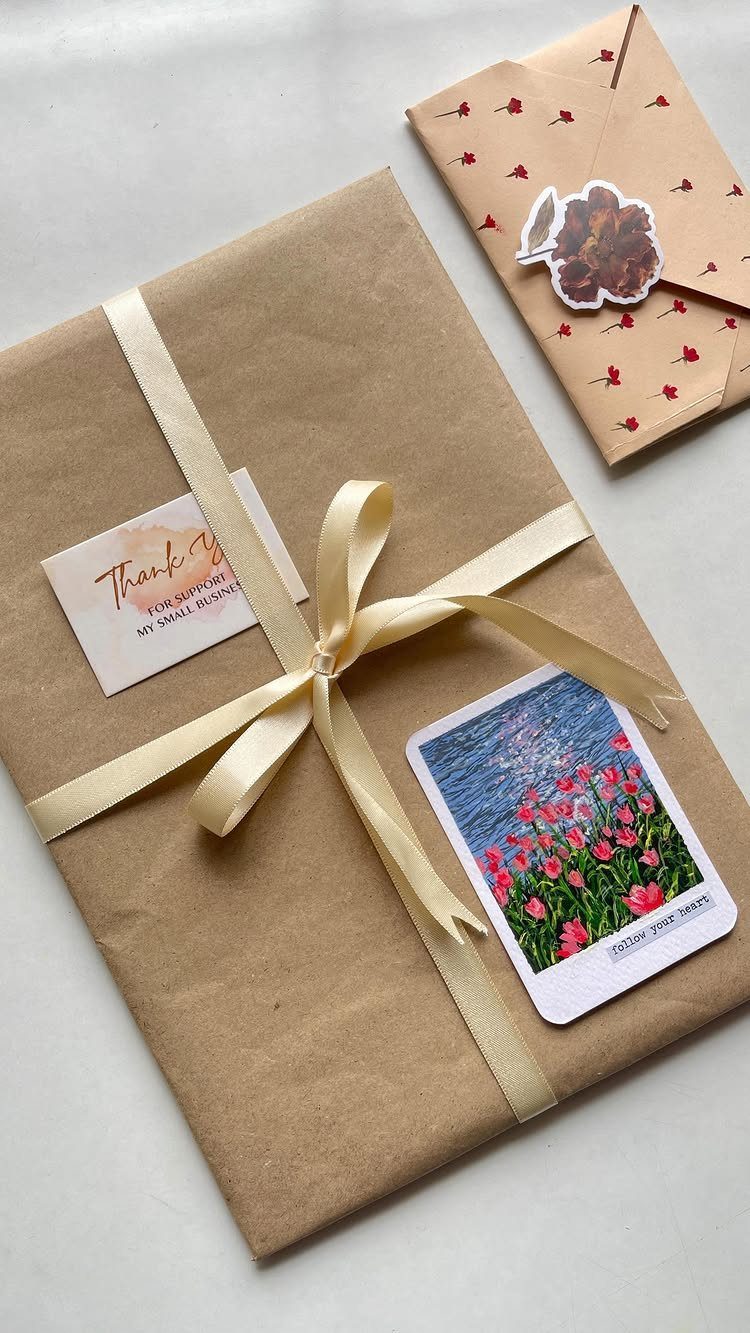 Brown paper wrapped gift with cream ribbon, thank you card, and floral postcard.