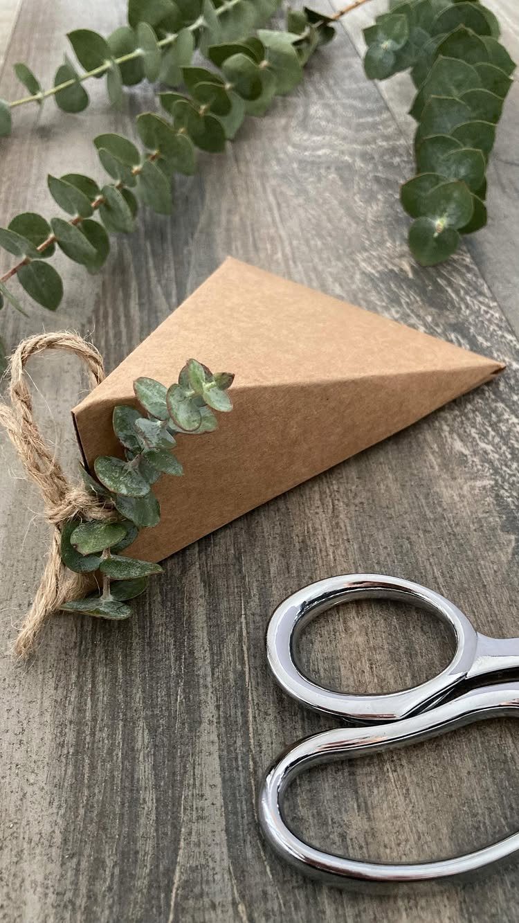 Brown paper wrapped gift with twine bow and eucalyptus on wooden background