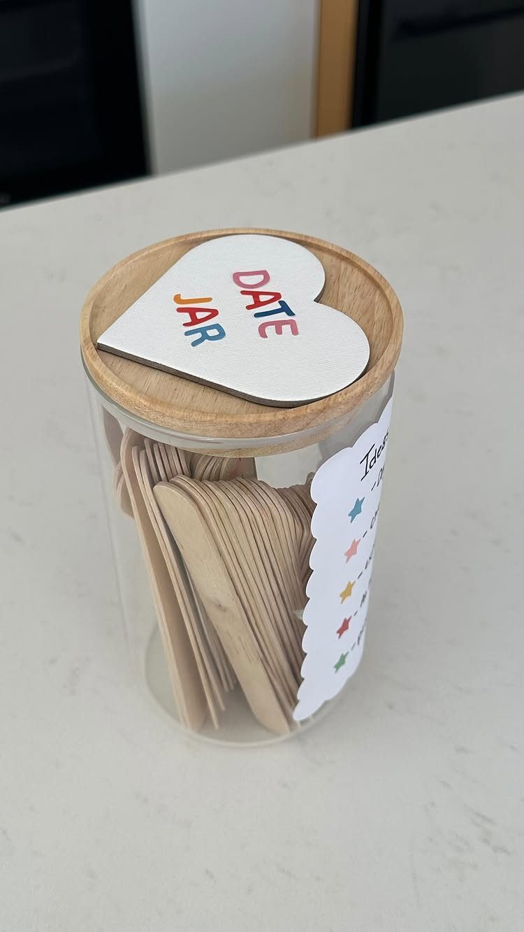 Date jar with wooden sticks and a heart-shaped lid on white surface