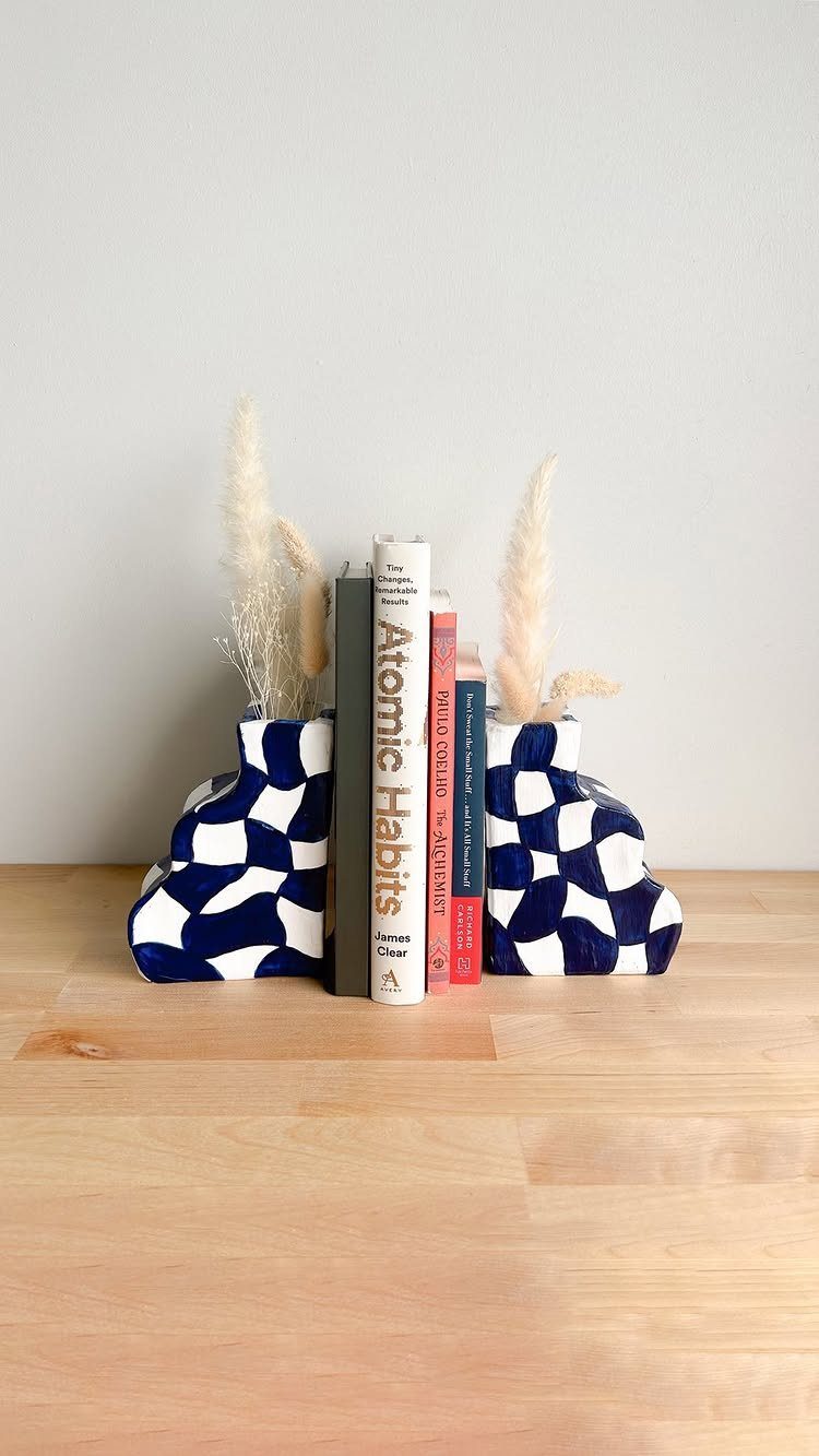 Blue and white checkered ceramic bookends holding books with dried pampas grass.