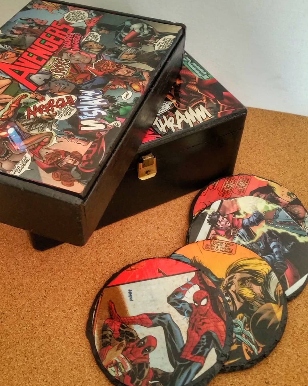 Comic book page coasters and a matching storage box on a cork background.