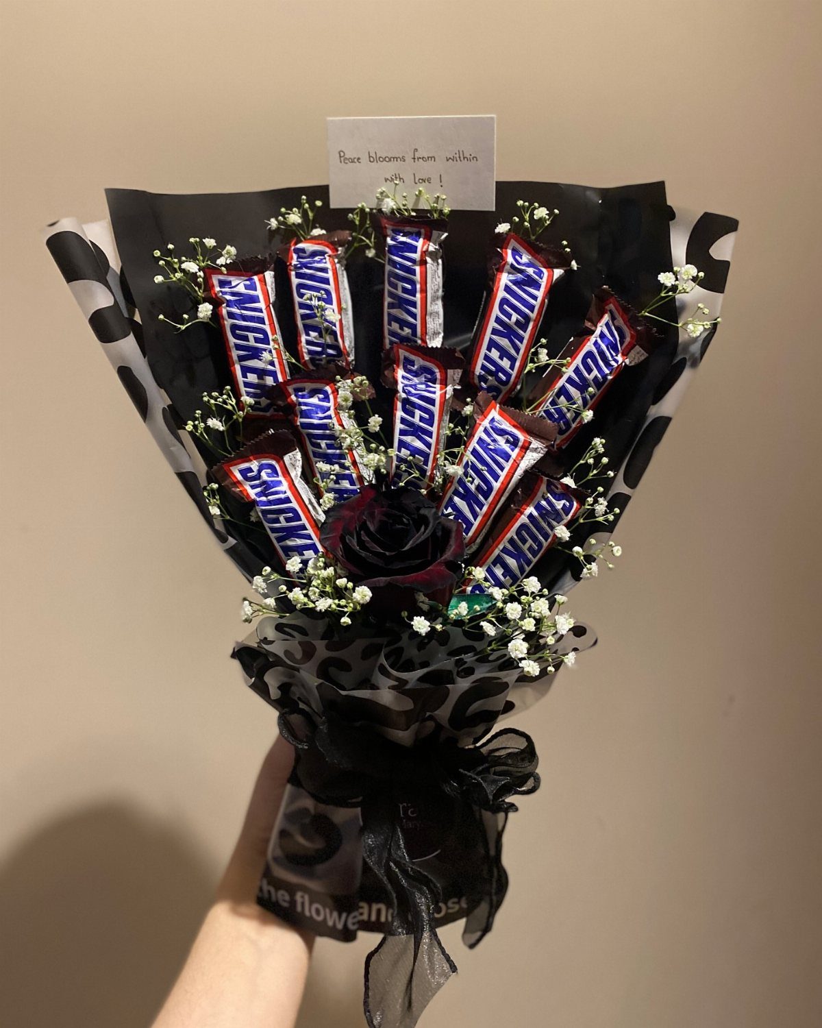 Bouquet of Snickers chocolate bars with a red rose and baby's breath flowers.