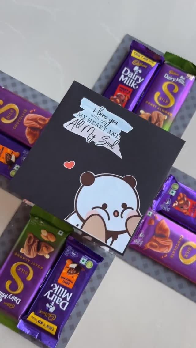 Handmade panda love card surrounded by purple chocolate bars on a white surface.