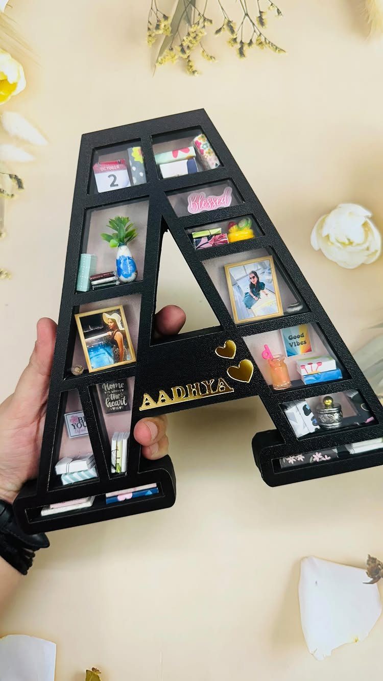 A-shaped black shadow box filled with miniature photos and small decorative trinkets.