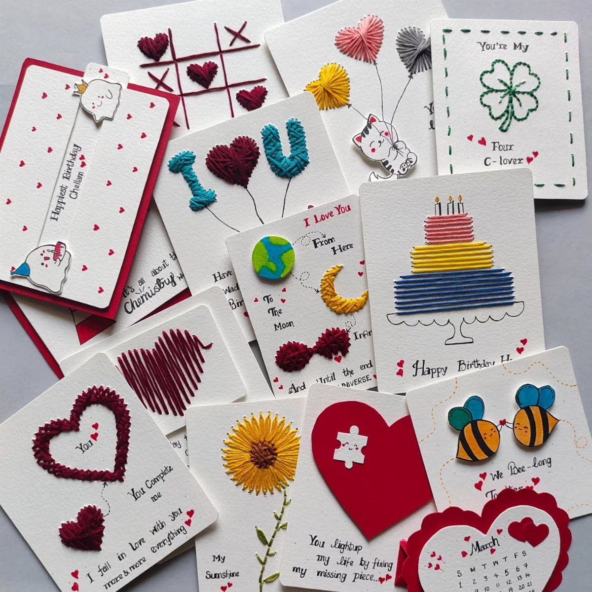 Handmade white cards with colorful embroidered hearts, flowers, and a birthday cake.
