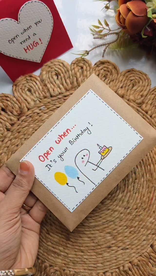 Brown envelope containing a handmade birthday card with a cute character and balloons.