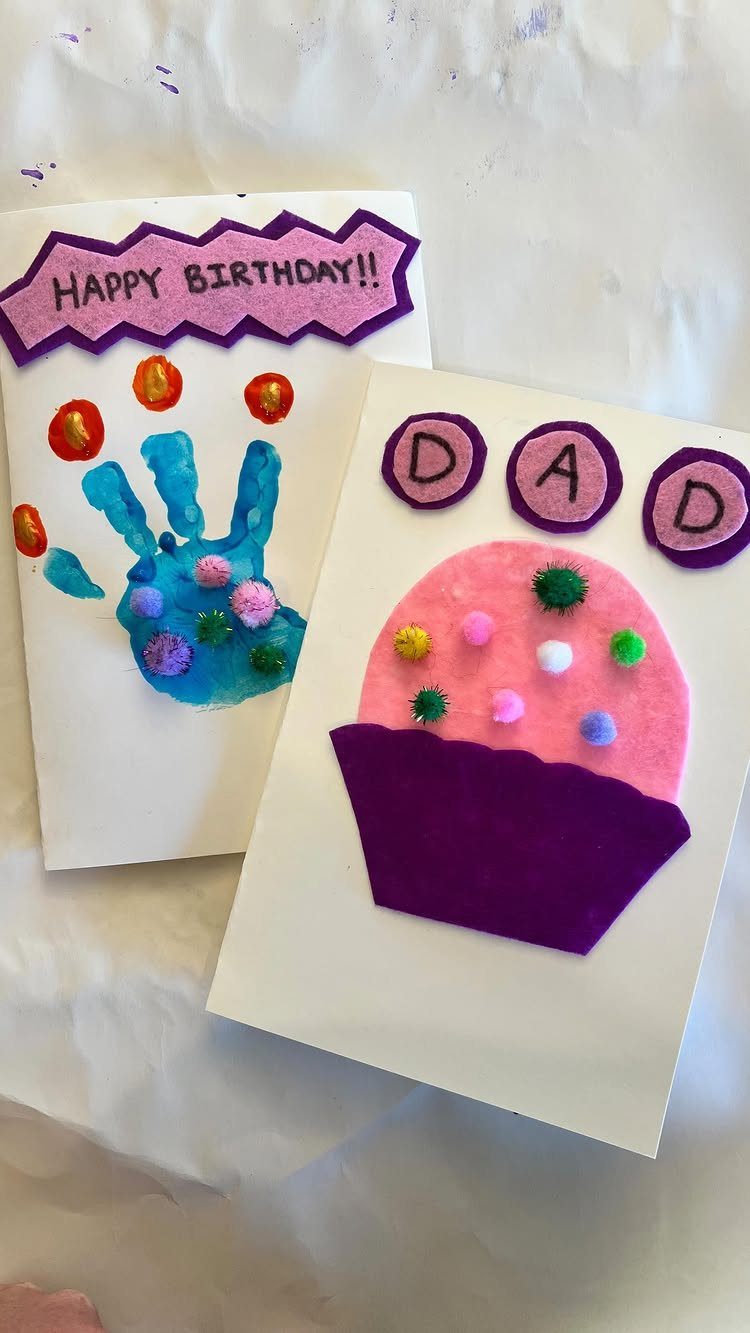 Two handmade birthday cards featuring colorful pom poms, a handprint, and a cupcake.