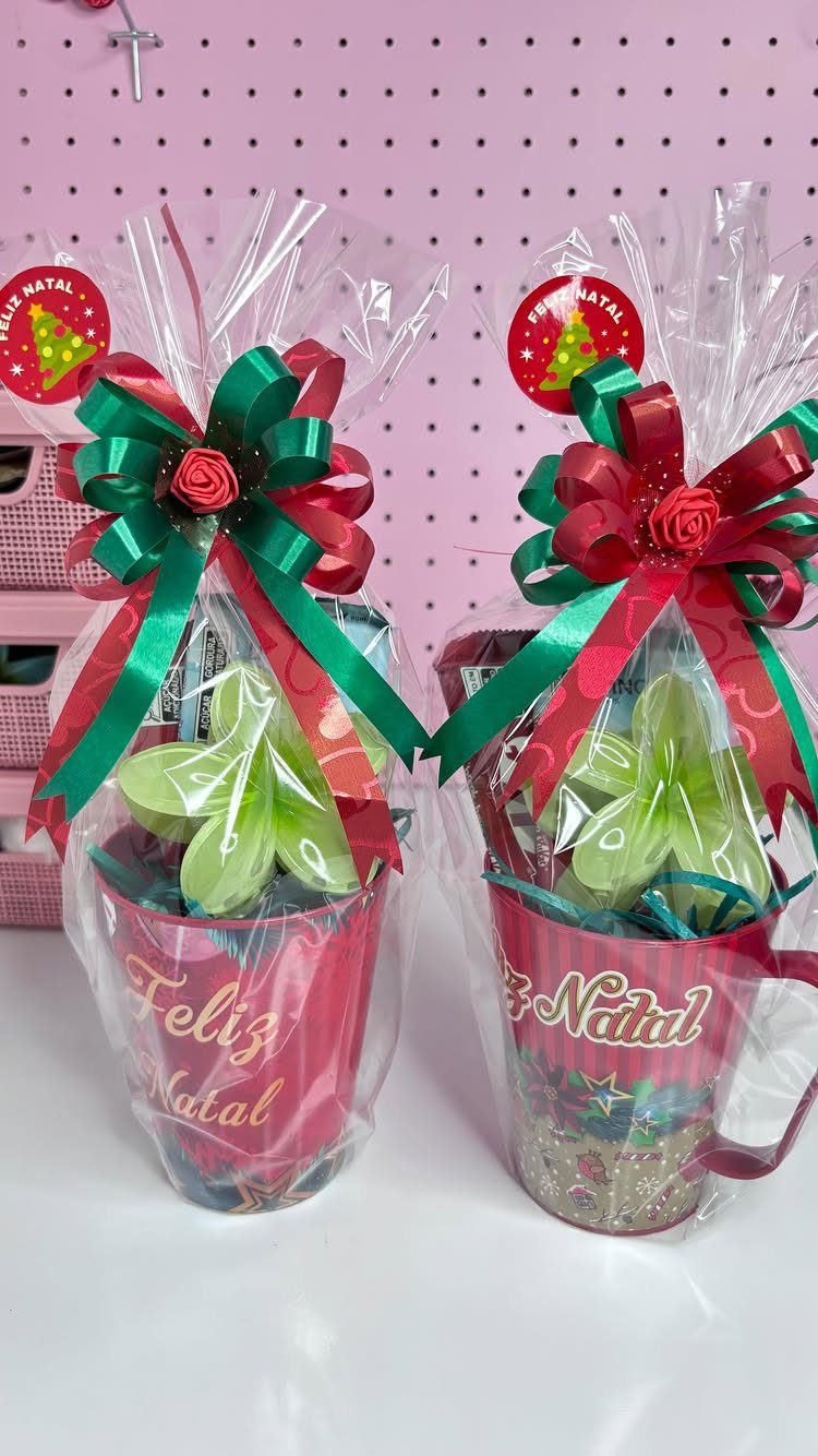 Two red mugs wrapped in clear cellophane with red and green ribbons.