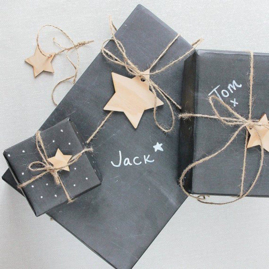 Black wrapped gifts with twine, wooden stars, and white handwritten names.
