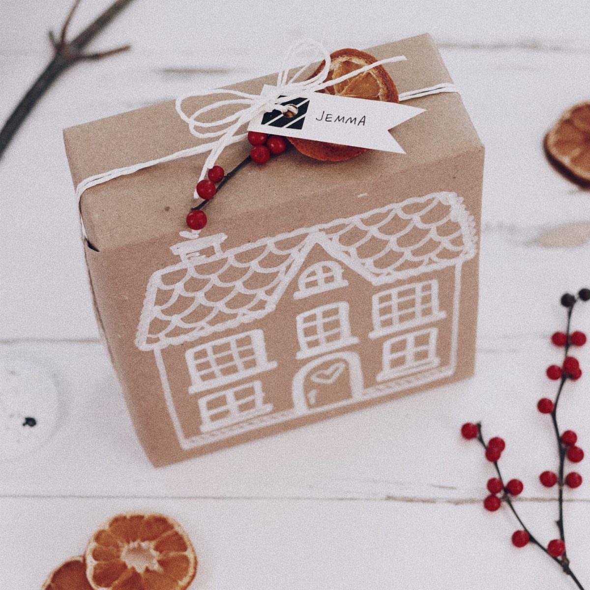 Kraft paper wrapped gift with a white house drawing and dried orange slice.