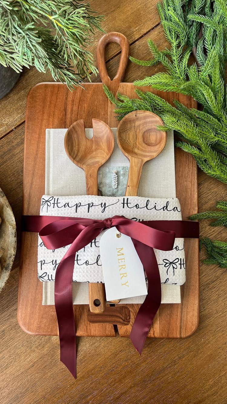 Wooden cutting board gift set wrapped in a holiday tea towel and burgundy ribbon.