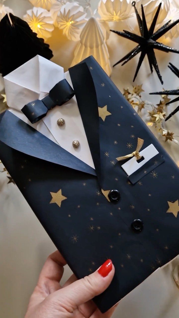 Gift wrapped as a navy blue tuxedo with gold stars and a bow tie.