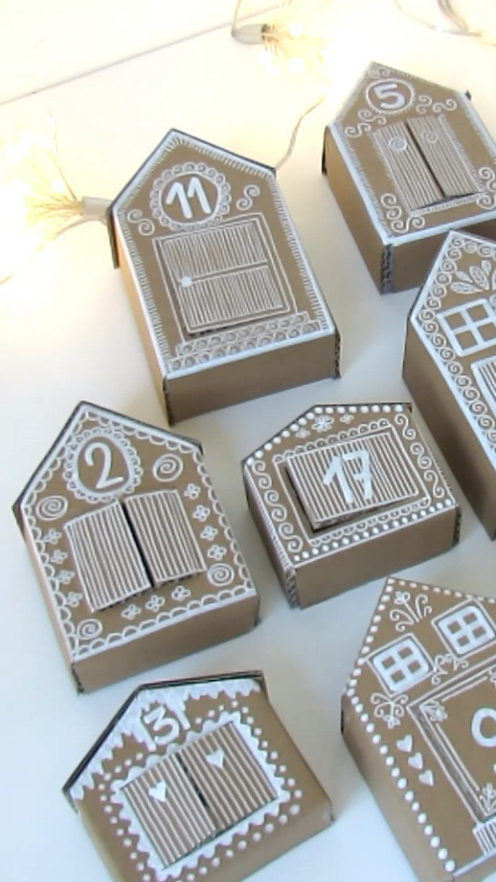 Brown cardboard house-shaped boxes with white numbers and drawings for an advent calendar.