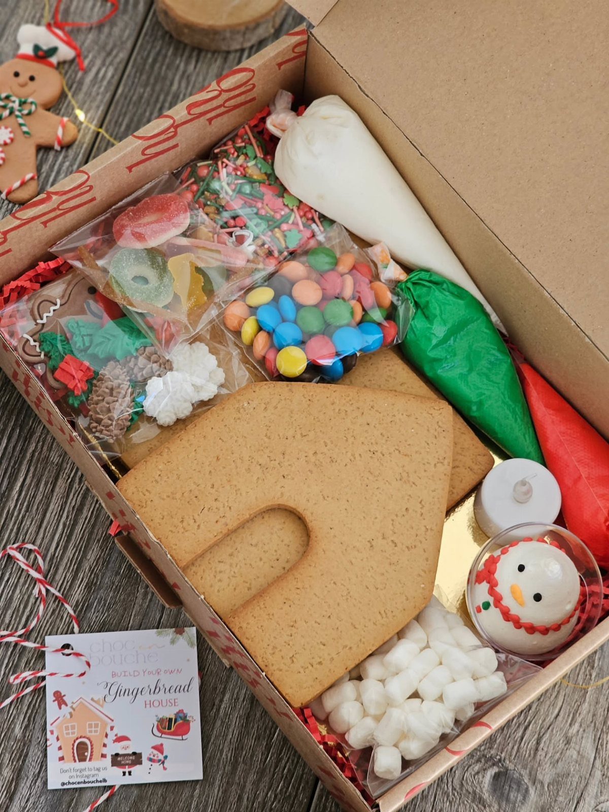 Gingerbread house kit in a box with icing, candies, and marshmallows.