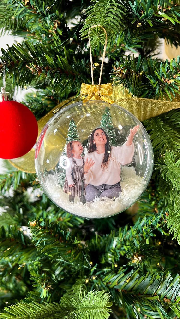 Clear glass Christmas bauble containing a photo of a woman and child in snow