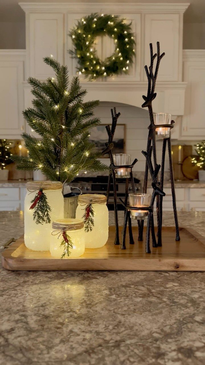 Glowing frosted jars and branch candle holders on a wooden tray for Christmas