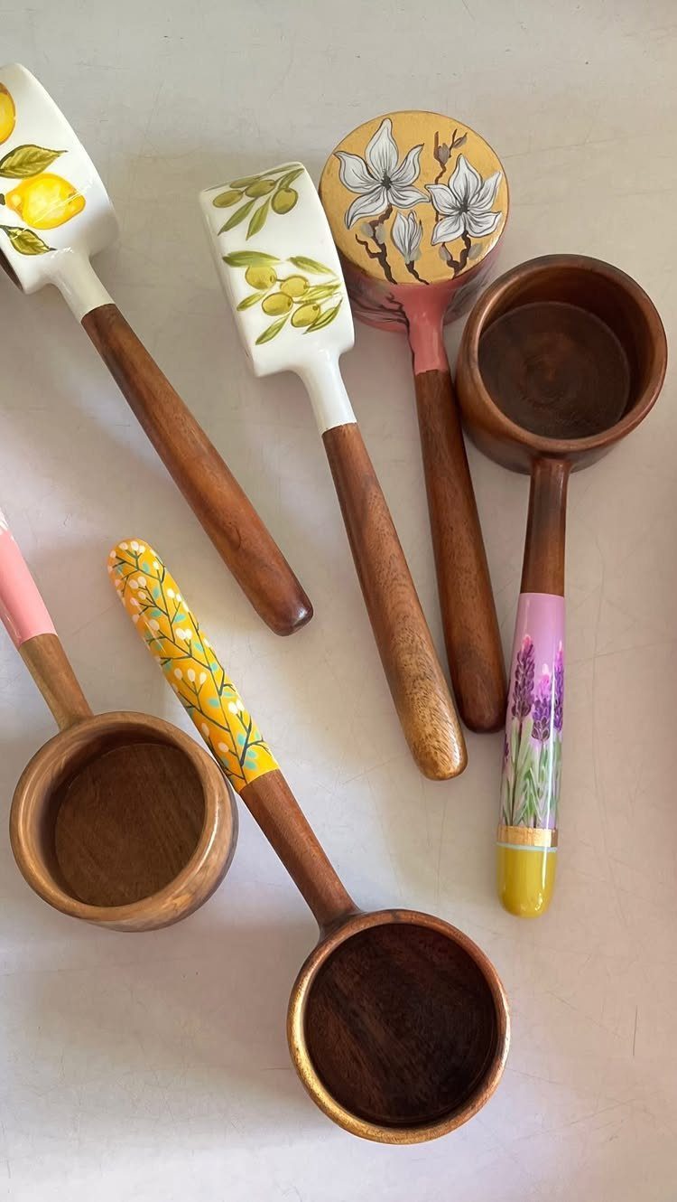 Hand-painted wooden kitchen utensils with floral and lemon designs on a light background