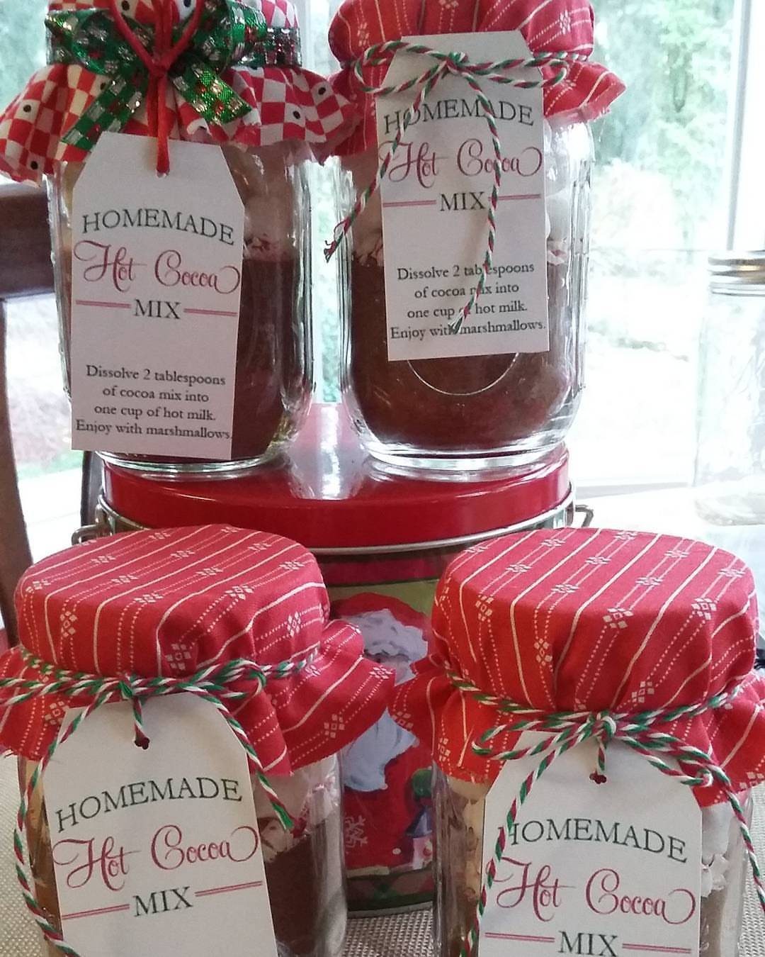 Mason jars filled with homemade hot cocoa mix topped with festive fabric covers.