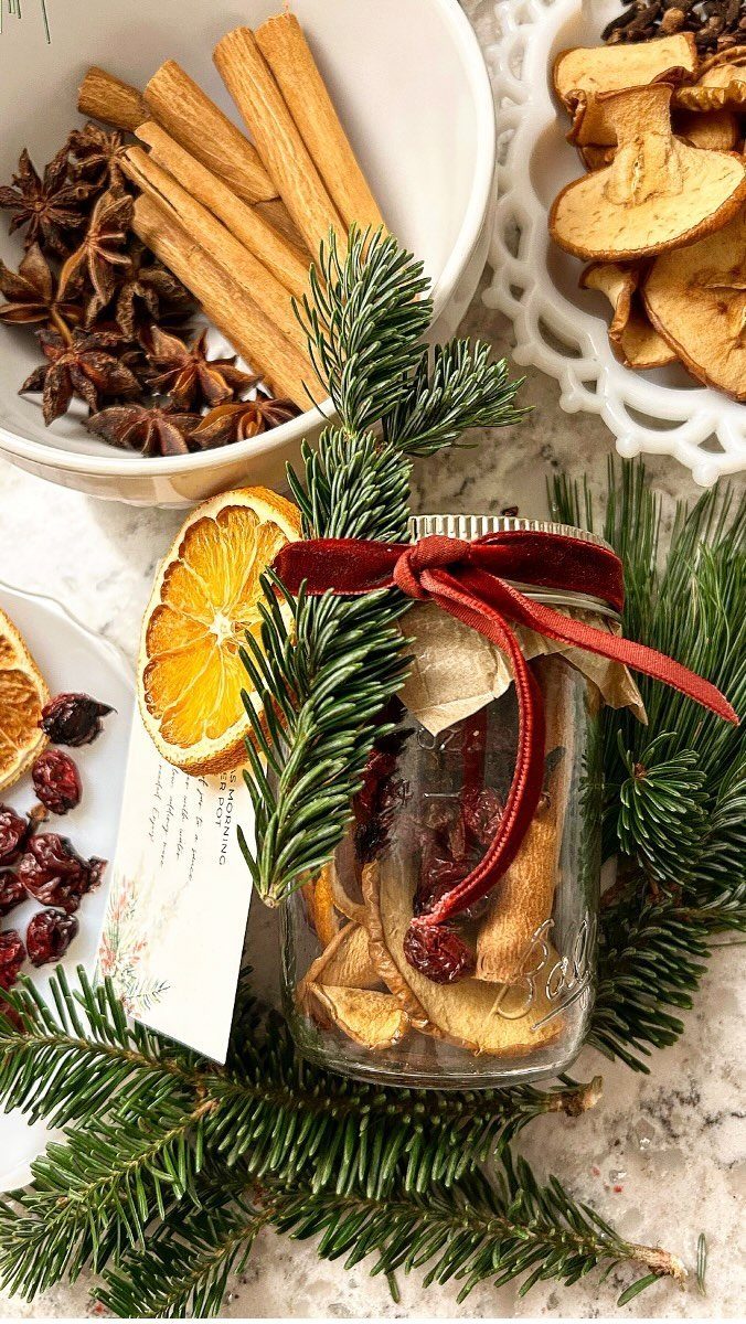 Mason jar filled with dried fruit treats tied with red ribbon and evergreen