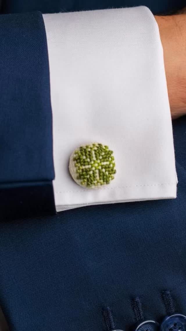 Beaded green and white cufflink on a white shirt cuff and navy suit.