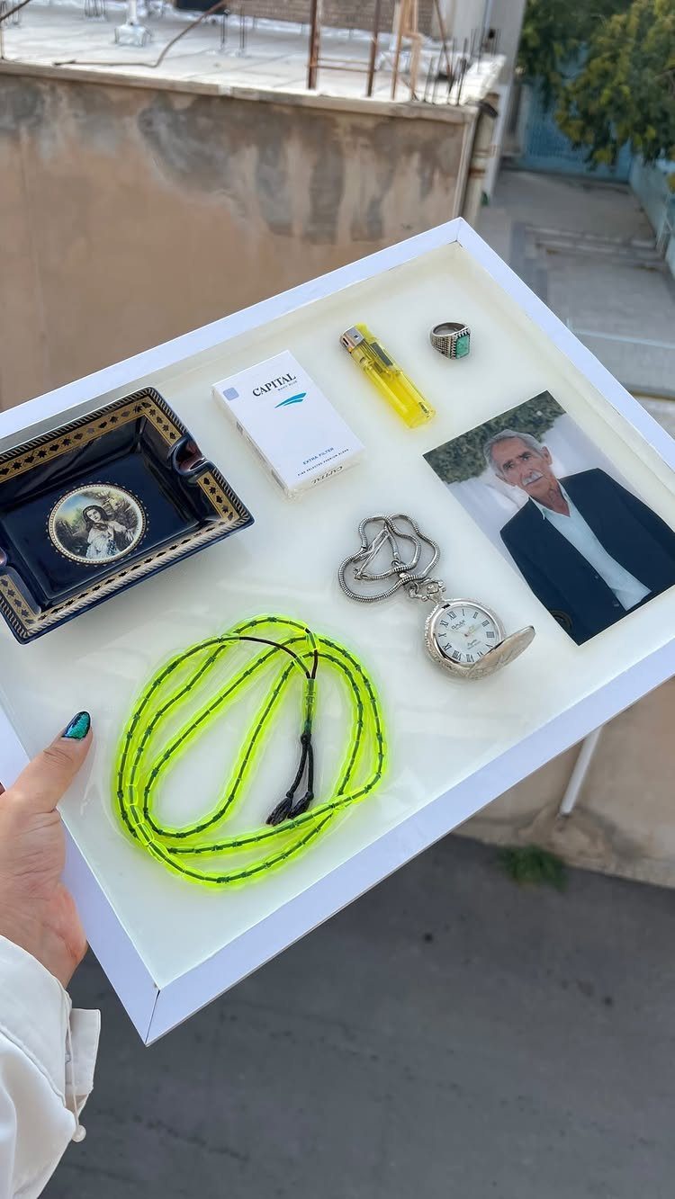 White shadowbox containing a man's photo, pocket watch, and personal mementos.