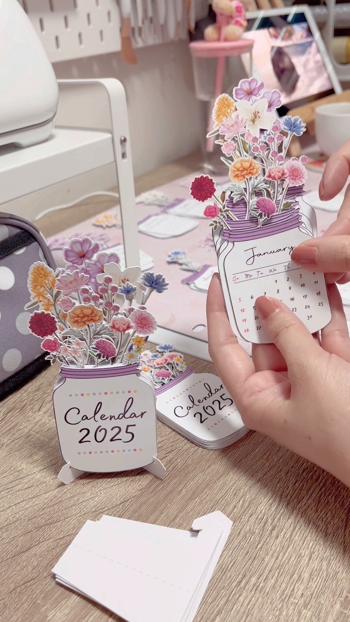 Handmade paper jar calendars with colorful 3D flowers on a wooden table
