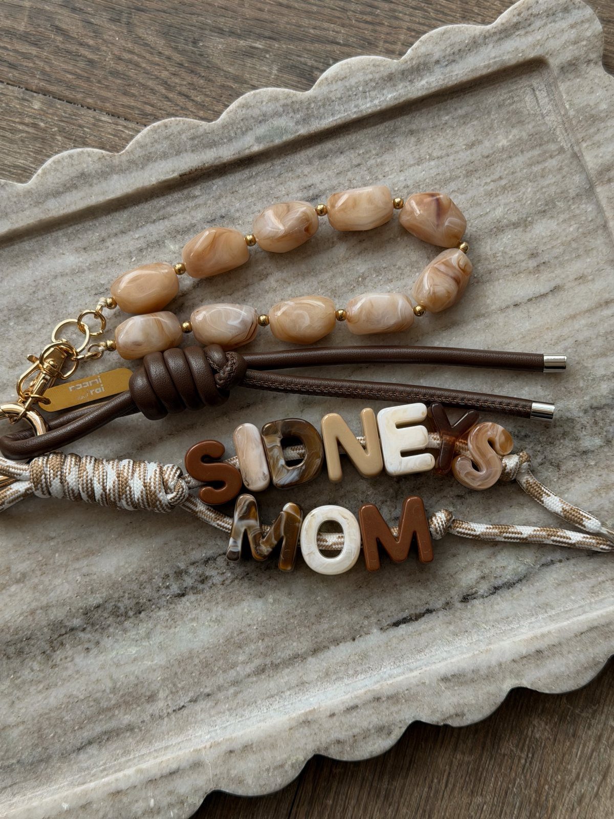 Handmade beaded and leather bracelets on a white scalloped marble tray.