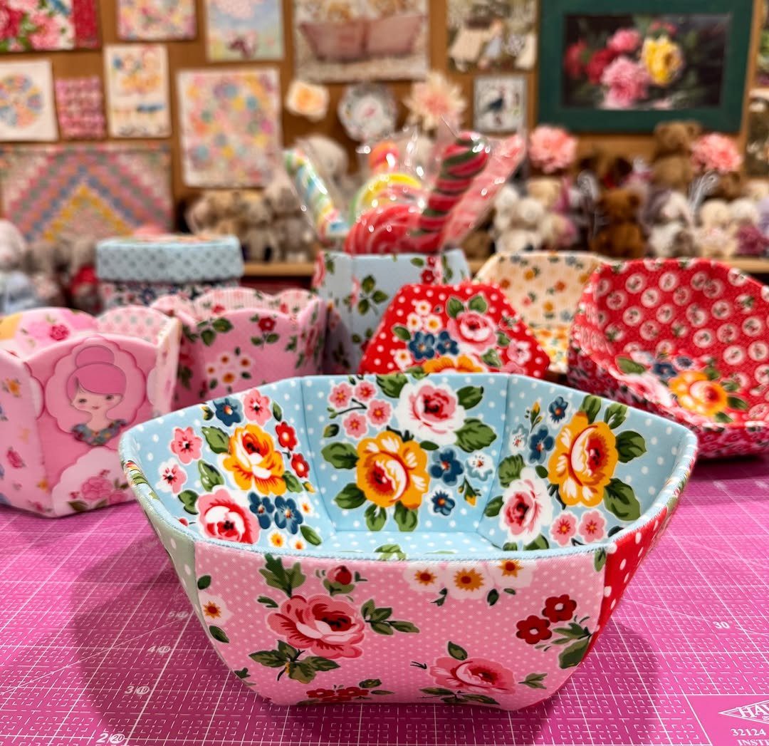 Fabric covered pots with colorful floral patterns sitting on a pink cutting mat.