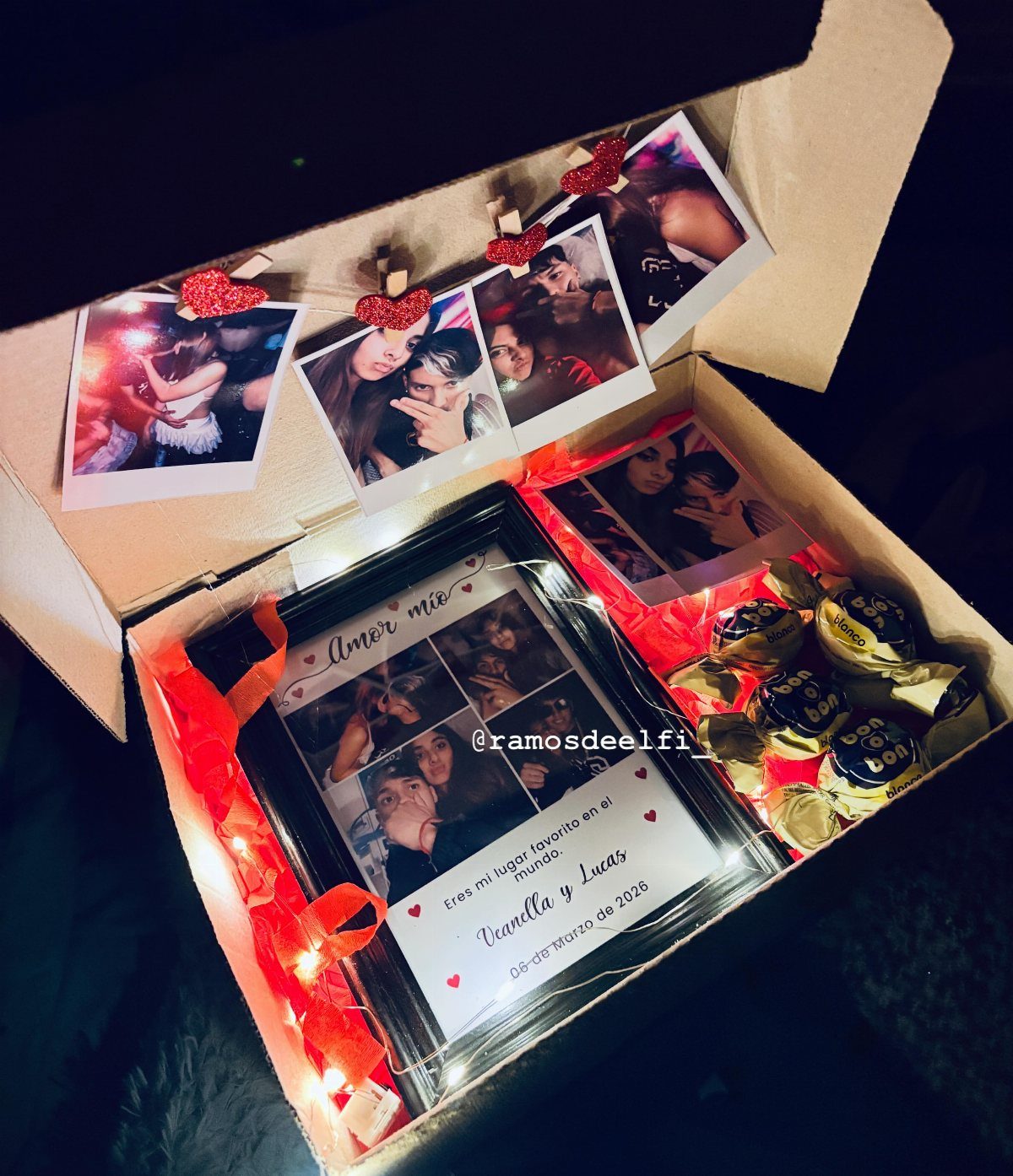 Cardboard gift box filled with a framed photo collage, polaroids, and chocolates.