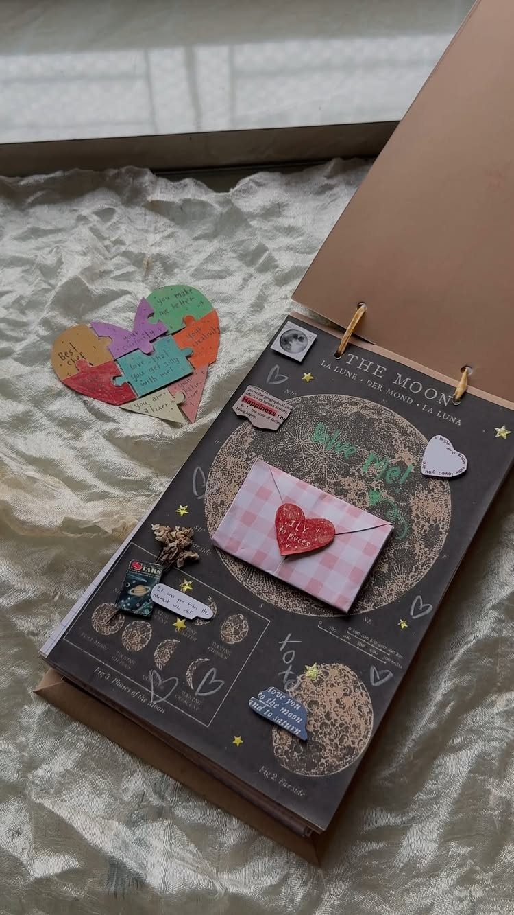 Open scrapbook page with a moon, red heart envelope, and heart-shaped puzzle pieces.