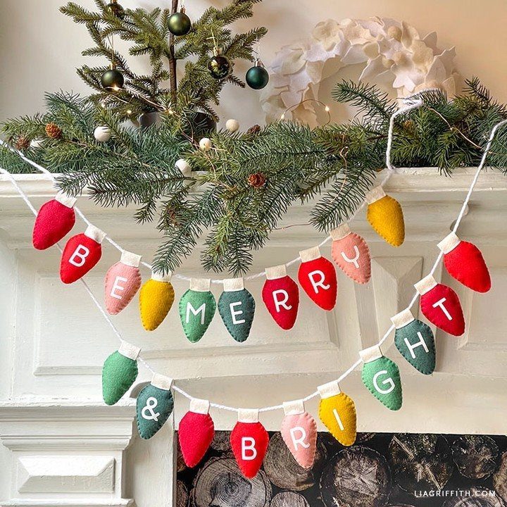 Colorful felt bulb garland spelling Be Merry and Bright on a white mantel