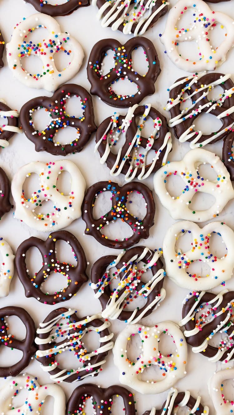 Chocolate covered pretzels with colorful sprinkles and white chocolate drizzle on white background