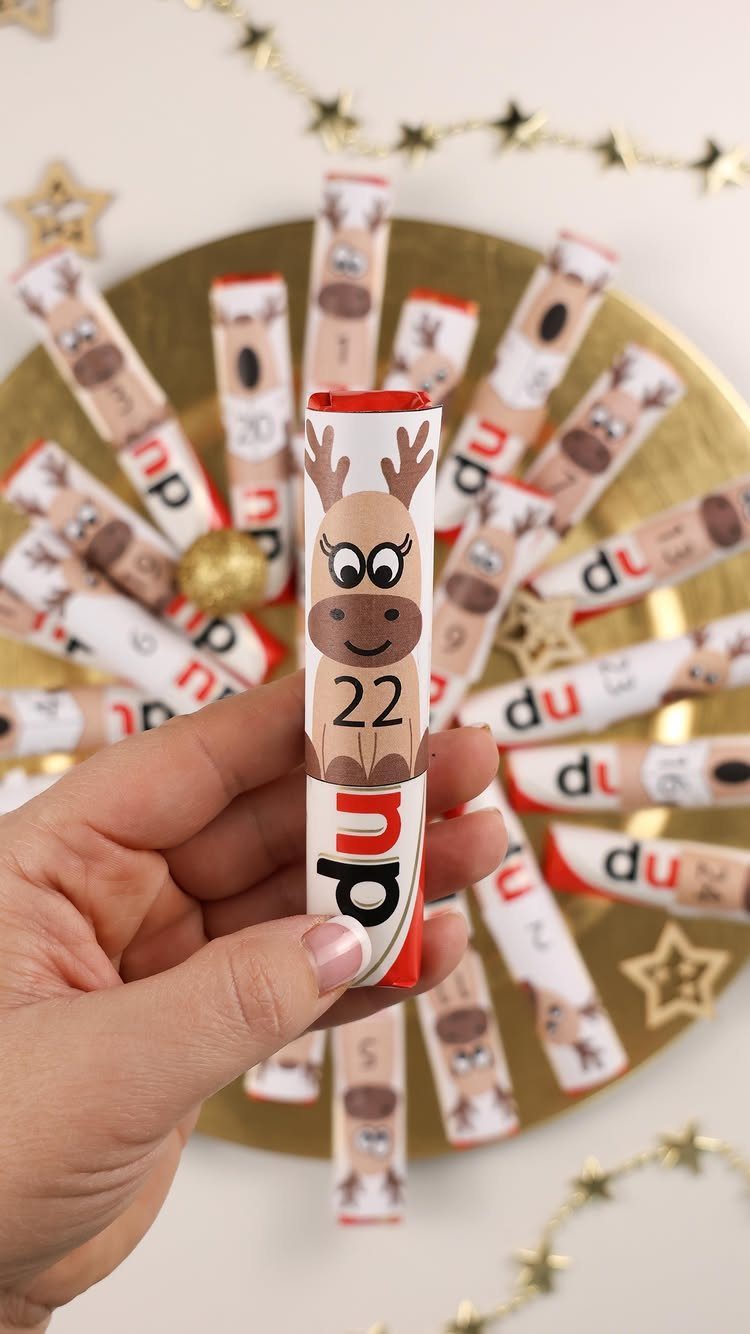 Hand holding a reindeer themed advent calendar scroll on a gold plate.