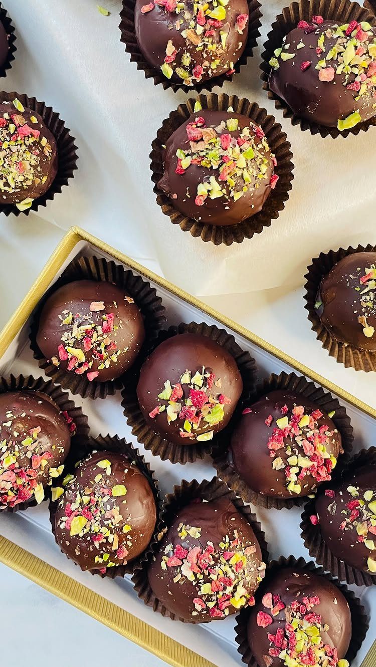 Chocolate truffles with colorful sprinkles in brown paper liners and a gold box