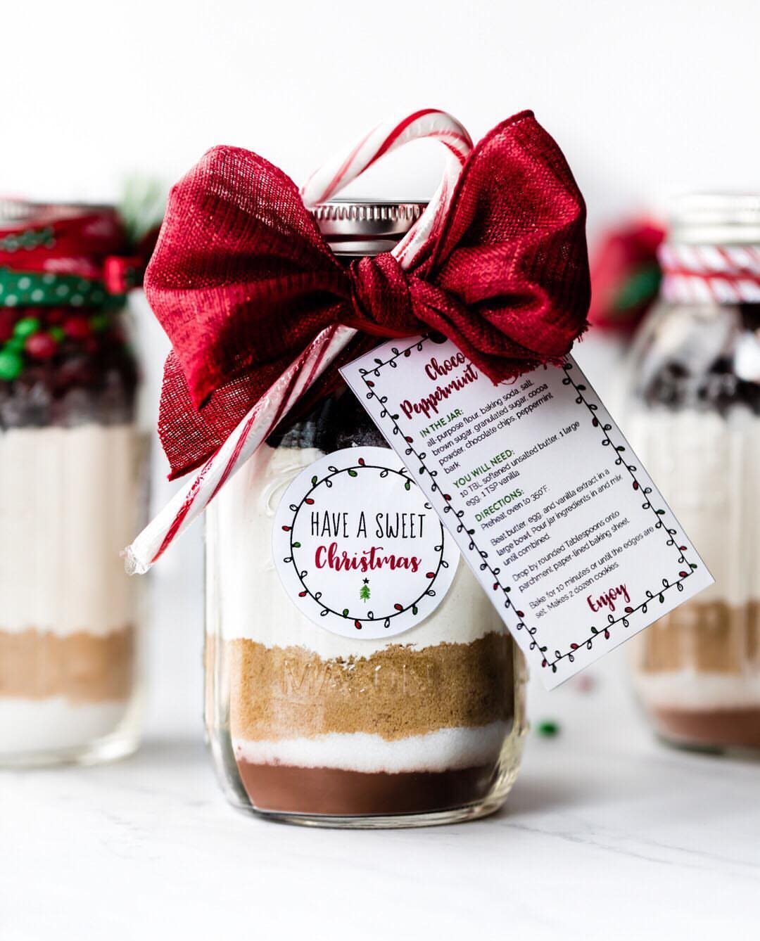 Layered cookie ingredients in a mason jar with a red bow and gift tag.