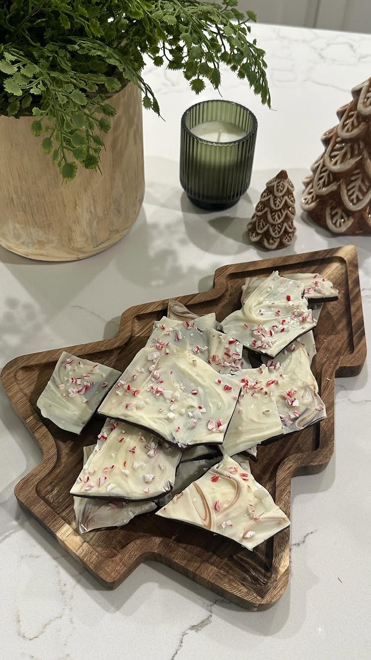 White chocolate peppermint bark on a wooden Christmas tree-shaped serving board.