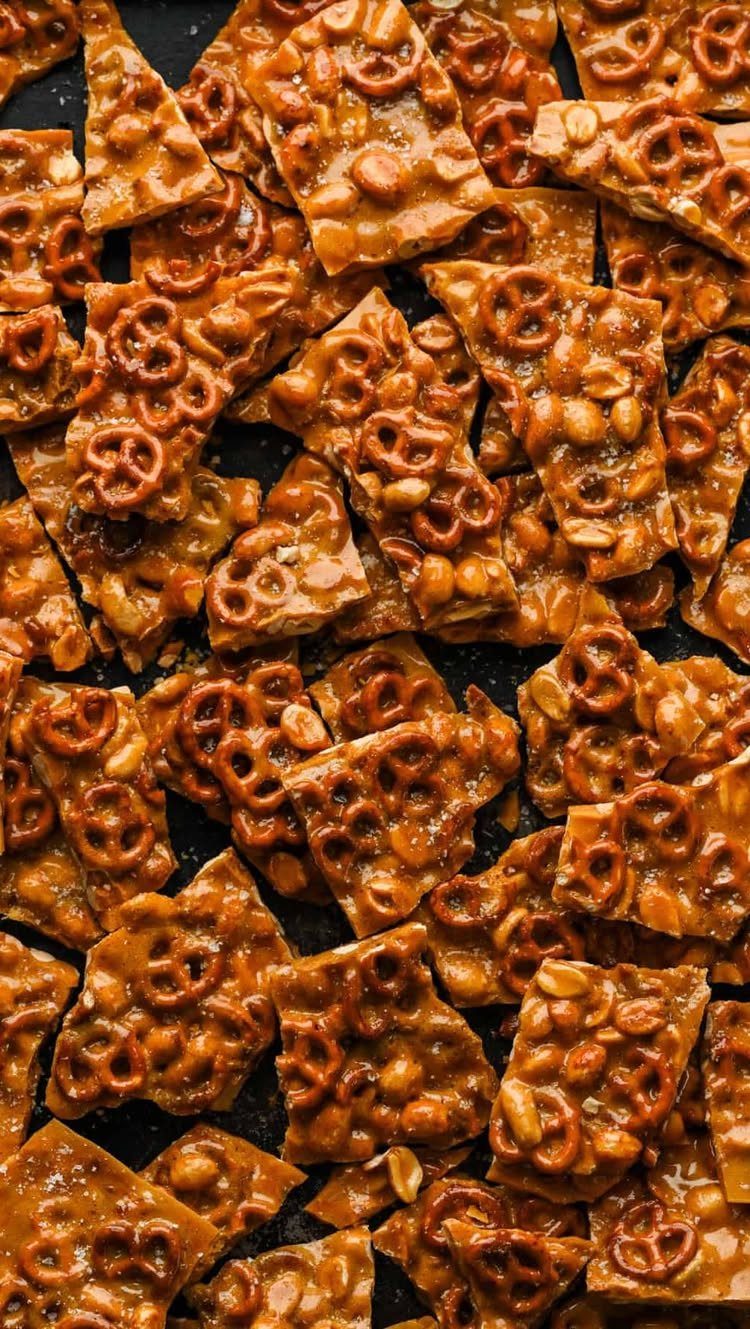 Peanut brittle pieces with embedded pretzels and peanuts on a dark background