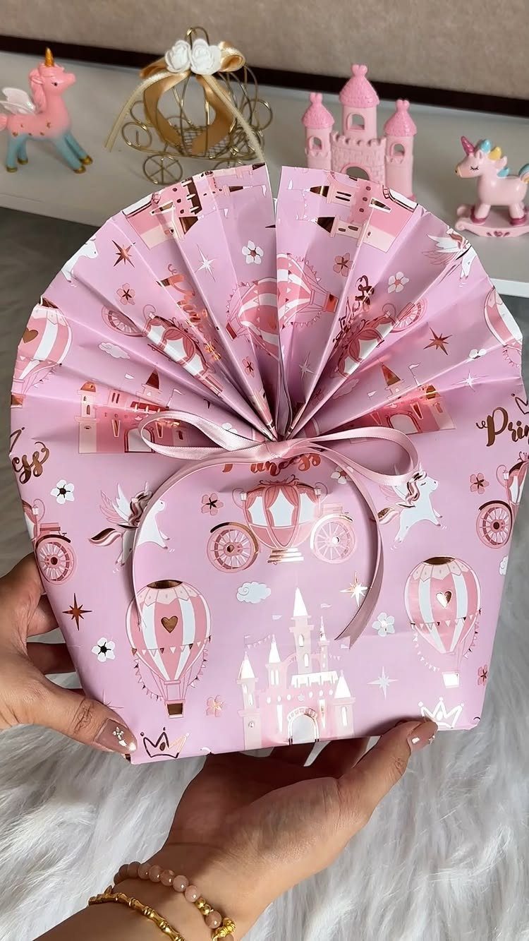 Gift wrapped in pink patterned paper with a fan-folded top and ribbon bow.
