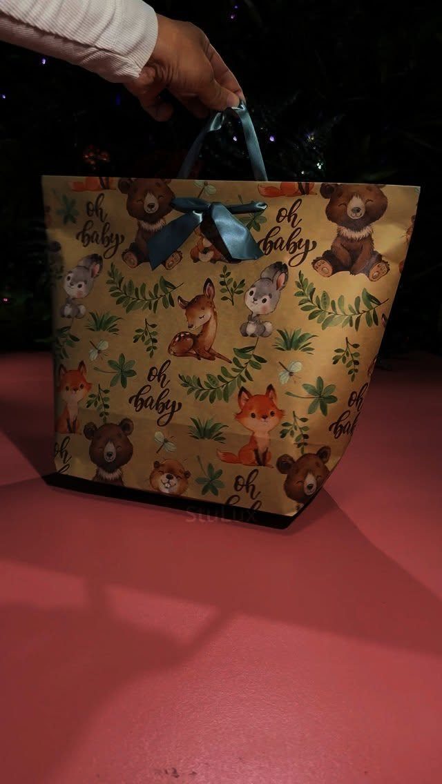 Handmade yellow gift bag with animal prints and blue ribbon handles.