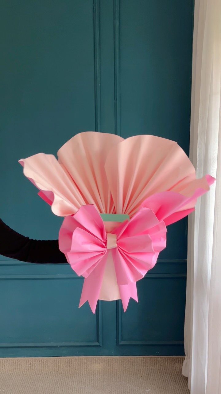 Bouquet wrapped in light pink paper with a large bright pink paper bow.