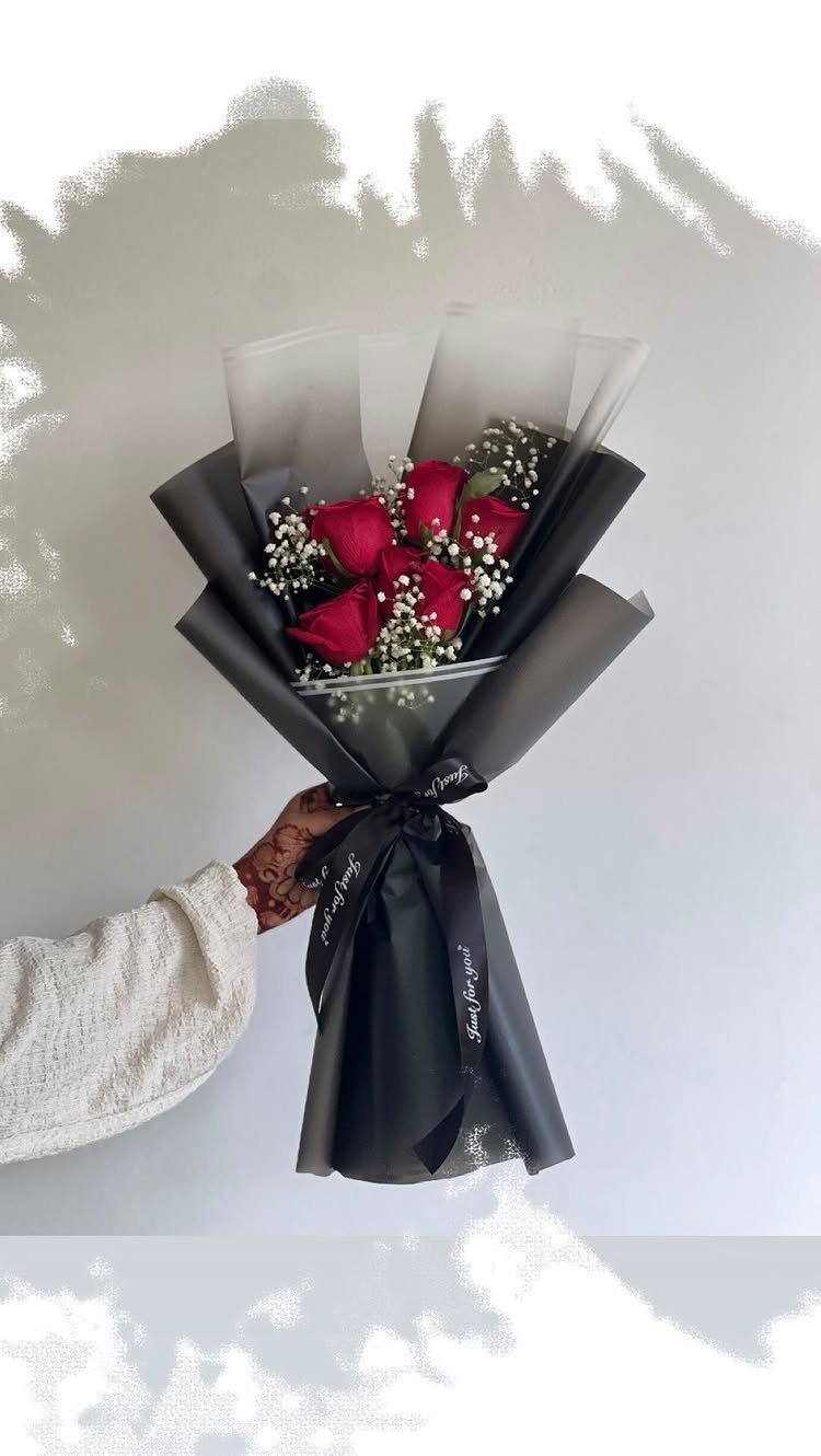 Bouquet of red roses wrapped in black and white paper with a ribbon.