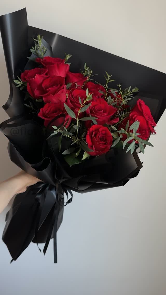 Red rose bouquet wrapped in black paper and tied with a black ribbon.