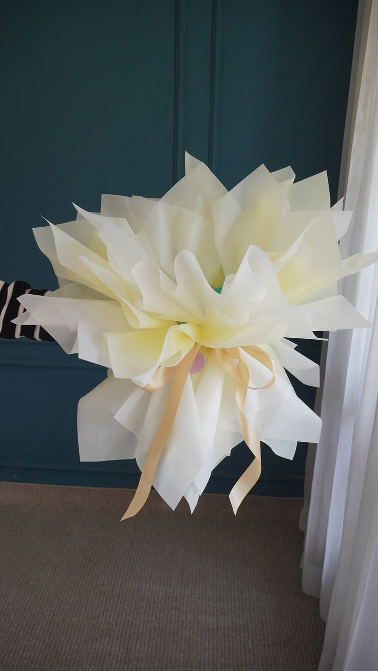 Bouquet of flowers wrapped in layered white and yellow paper with a ribbon.