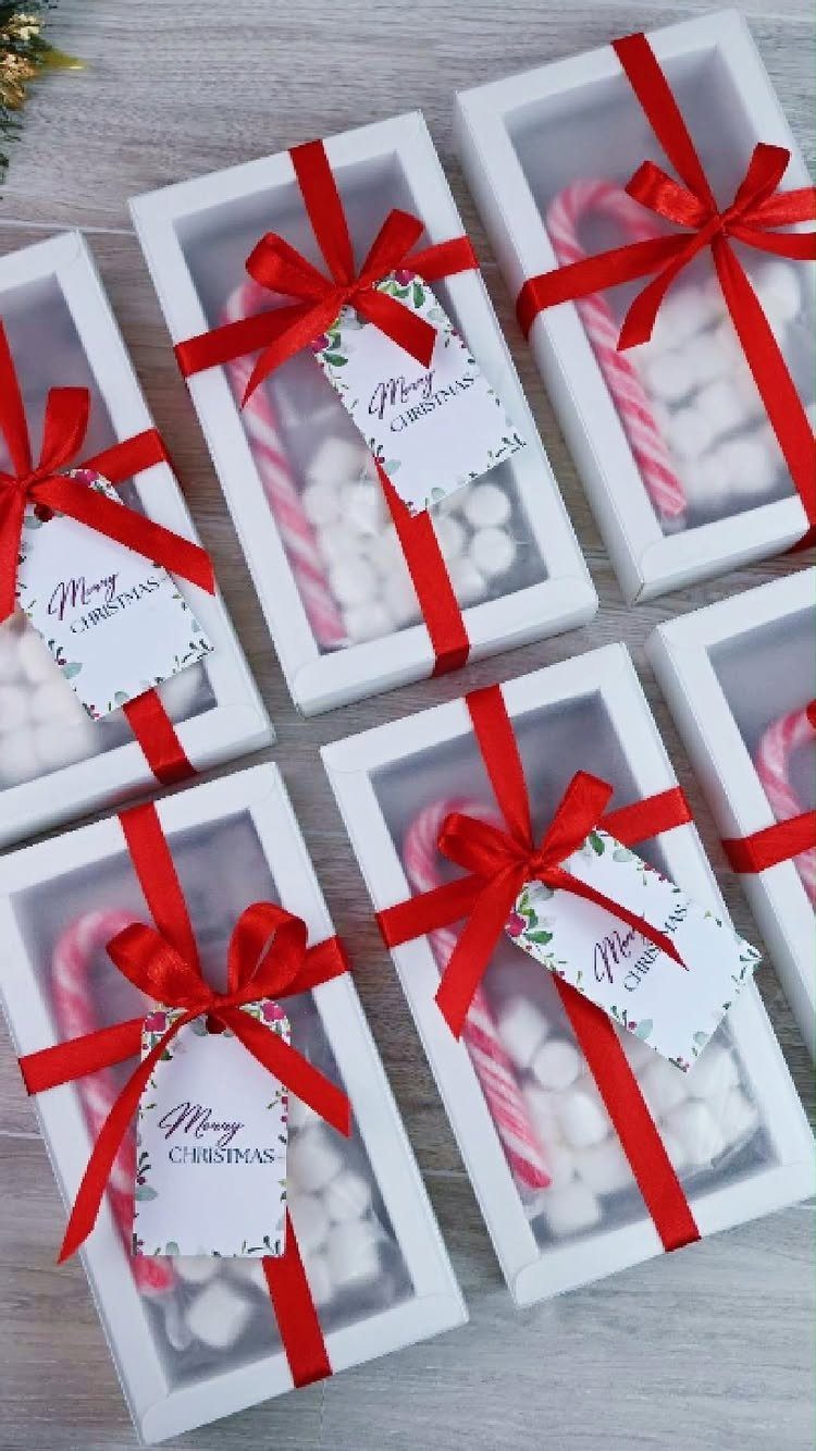 White gift boxes containing candy canes and marshmallows tied with red ribbons.