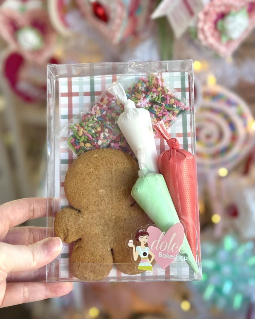 Gingerbread man cookie with frosting piping bags and sprinkles in a clear box.